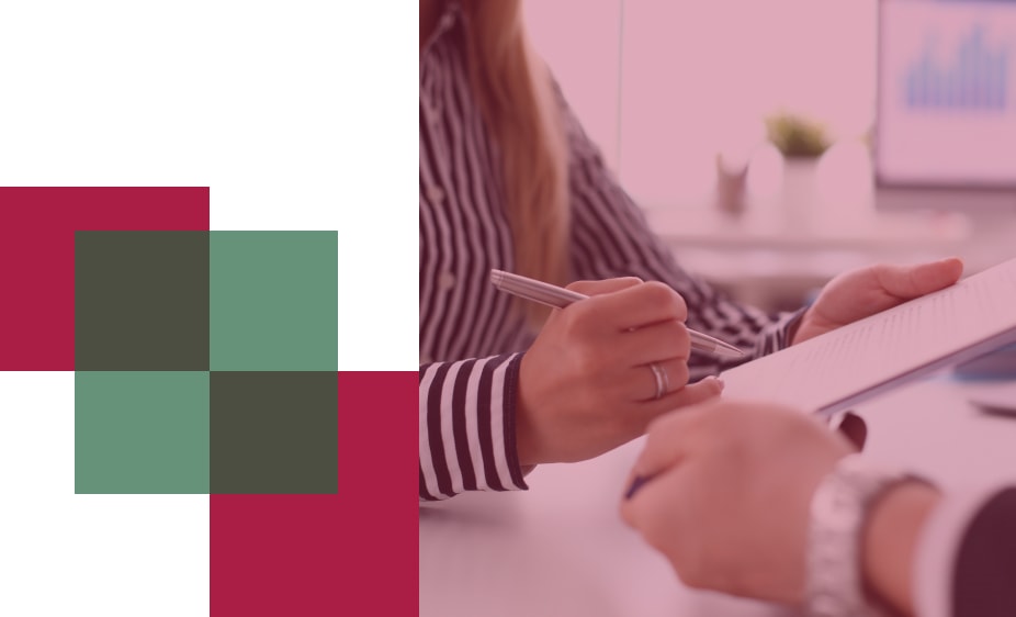 Pályázatok - a képen hivatali környezetben látható két ember, az egyik egy dokumentumot és egy tollat tart a kezeiben.